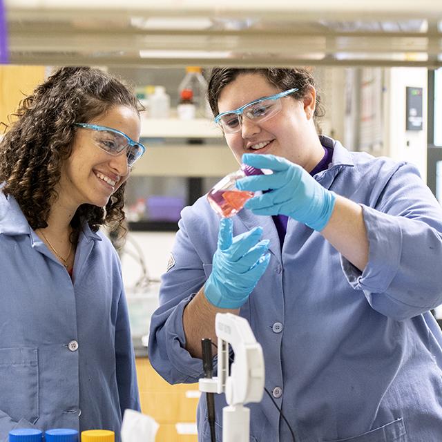 Female chemistry students discussing an experiment