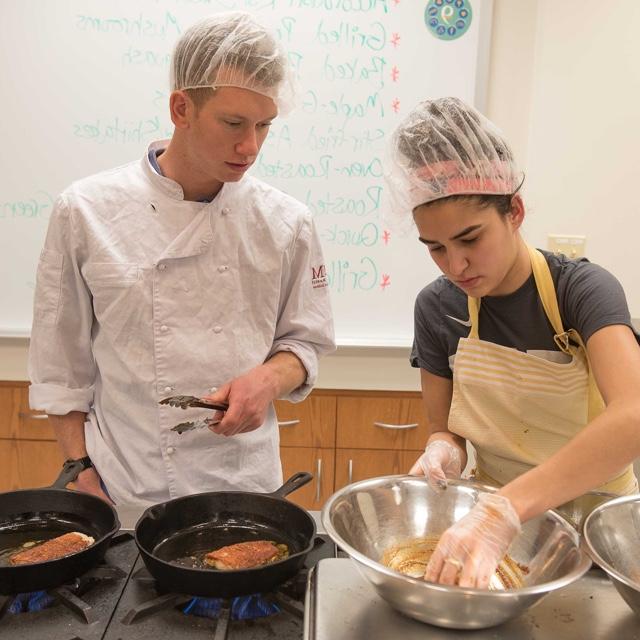 Food management students cooking fish on a cooktop